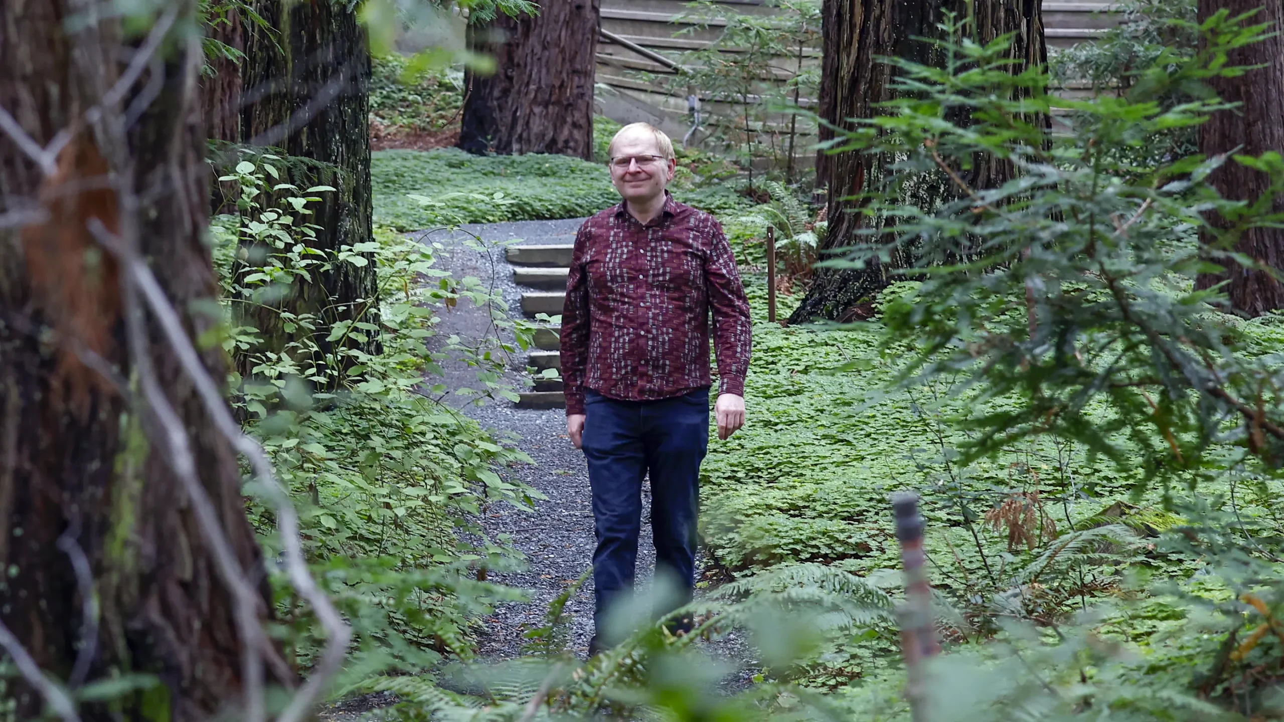 Alexei Efros in a red shirt standing among a few trees.